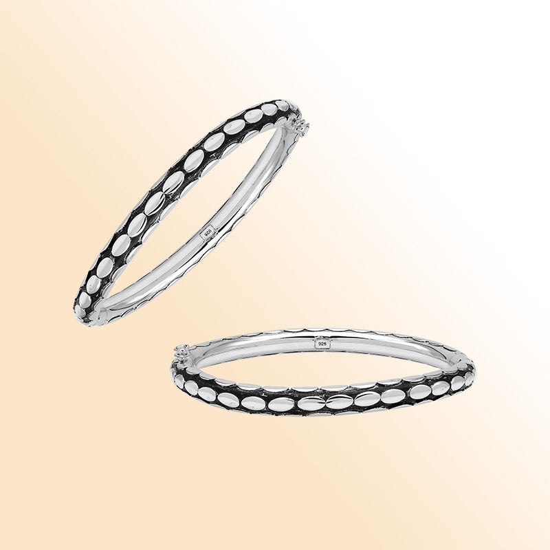 Handcrafted sterling silver medium bangle with elegant oval textured detailing, polished shine, and a secure hinge lock with safety latch for stylish daily wear.