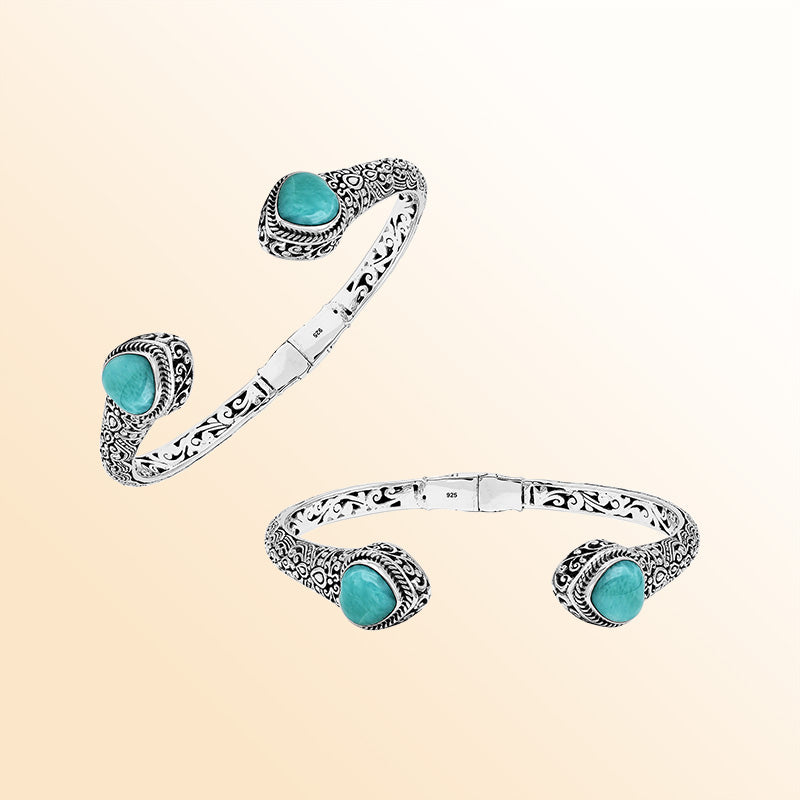 Handcrafted sterling silver bangle featuring two Larimar end stones, ornate Balinese scroll engravings, and a secure hinge lock for elegant, artisan-inspired everyday wear.