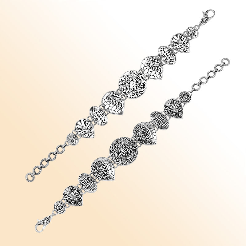 Handcrafted sterling silver link bracelet featuring carved Balinese scrollwork motifs across multiple shapes with oxidized details and a secure lobster lock closure.