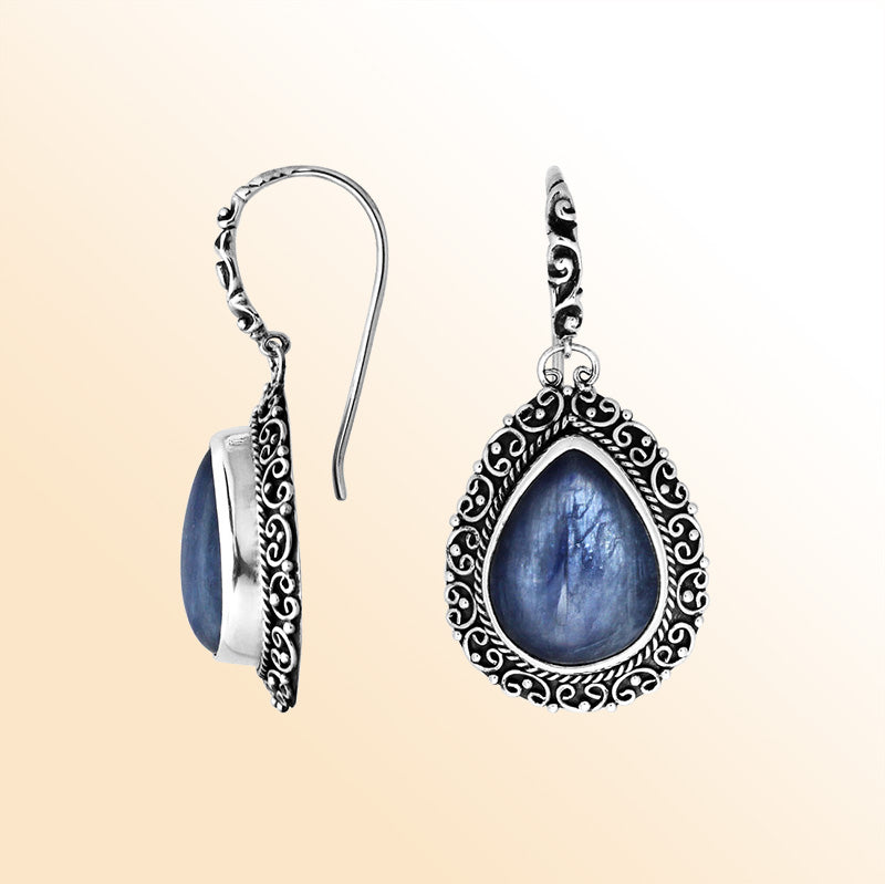 Sterling silver artisan earrings featuring pear-shaped kyanite cabochons surrounded by ornate Balinese-style detailing, designed to offer refined elegance, expressive artistry, and comfortable everyday wear.