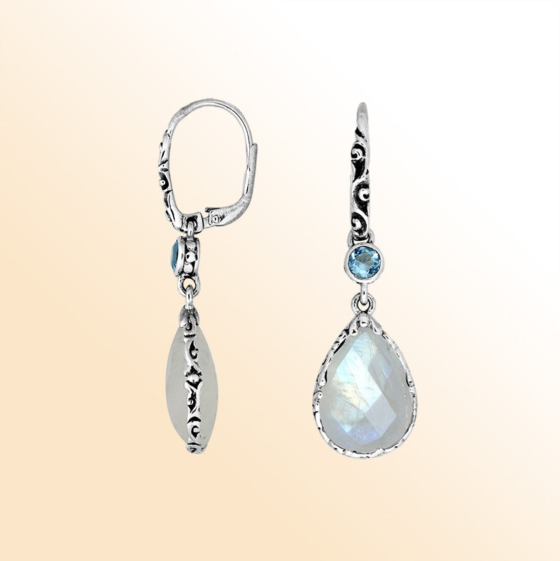 Elegant sterling silver dangle earrings featuring a shimmering Rainbow Moonstone teardrop and a bright Blue Topaz Quartz accent with ornate scroll details and earwire for a refined handcrafted look.