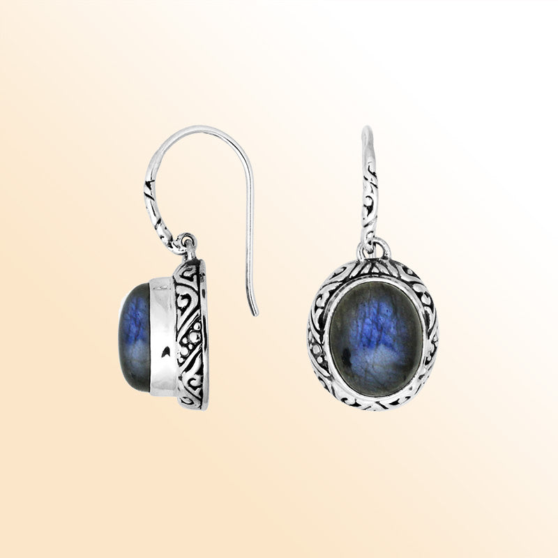 Sterling silver earrings featuring an oval Labradorite cabochon surrounded by artistic carved detailing with an earwire lock, offering luminous color play and handcrafted elegance for everyday wear.