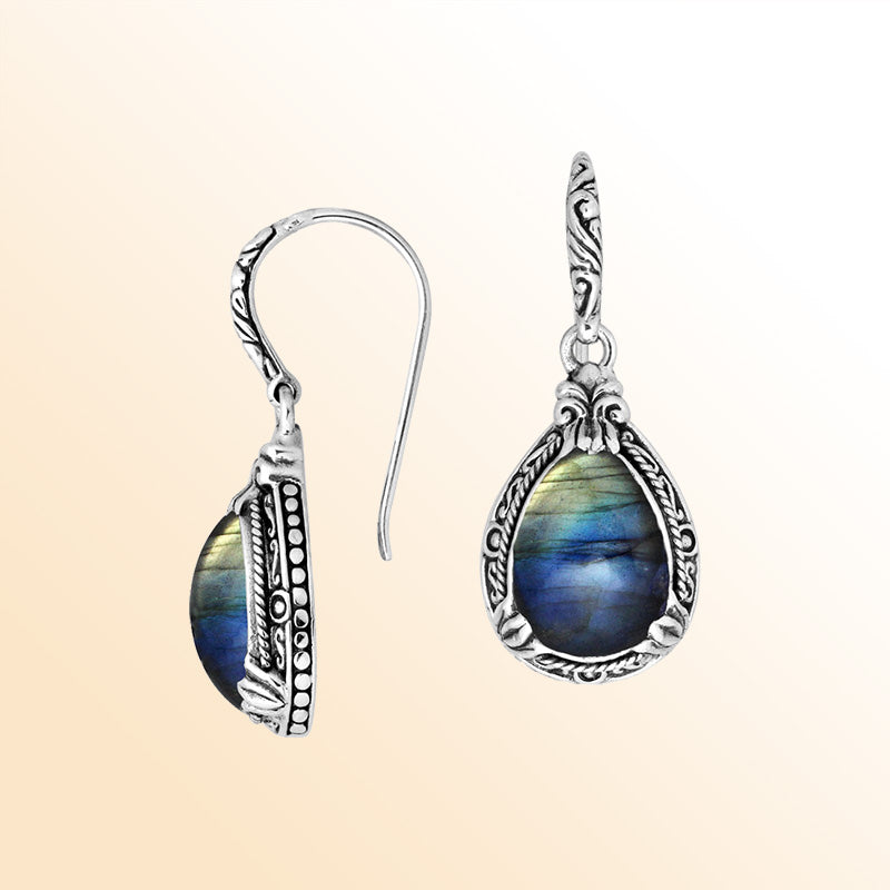 Sterling silver earrings featuring a glowing Labradorite teardrop with blue and gold iridescence, framed in ornate carved detailing and secured with an earwire lock for enchanting, handcrafted everyday elegance.