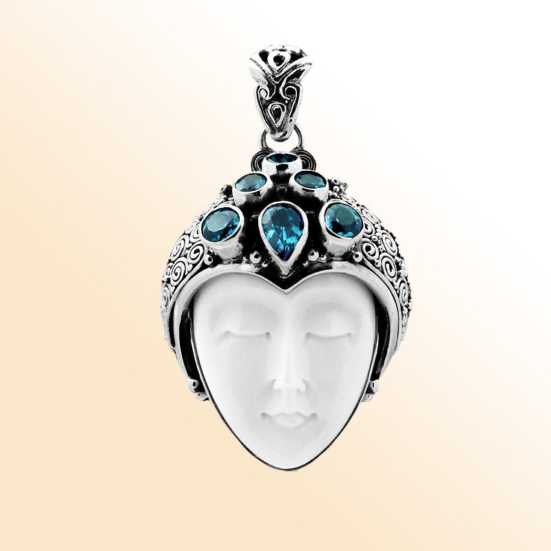 Wholesale sterling silver pendant with hand-carved bone goddess face and faceted blue topaz gemstones, handcrafted Balinese artisan jewelry design.