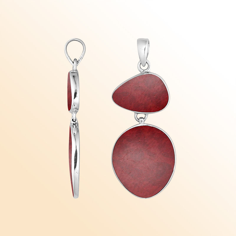 Handcrafted sterling silver pendant featuring red coral stones in triangular and oval shapes, smooth polished surface, and refined Balinese artistry.