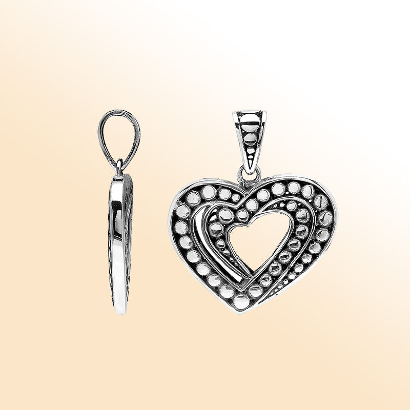 Handcrafted sterling silver heart-shaped pendant with layered open-heart design, dotted engravings, and oxidized Balinese detailing.