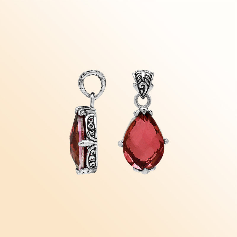 Handcrafted sterling silver pear-shaped pendant featuring a faceted Red Garnet Quartz centerpiece with expressive prong work and decorative Balinese carved detailing.