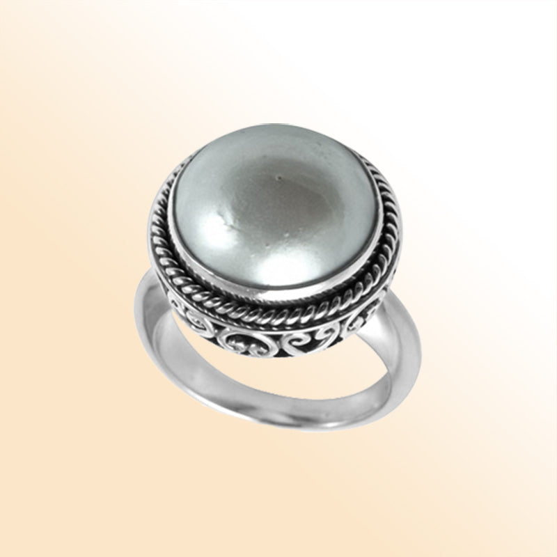 Sterling silver mother of pearl ring with polished cabochon stone, twisted rope bezel, and elegant Balinese scrollwork, handcrafted in Bali.