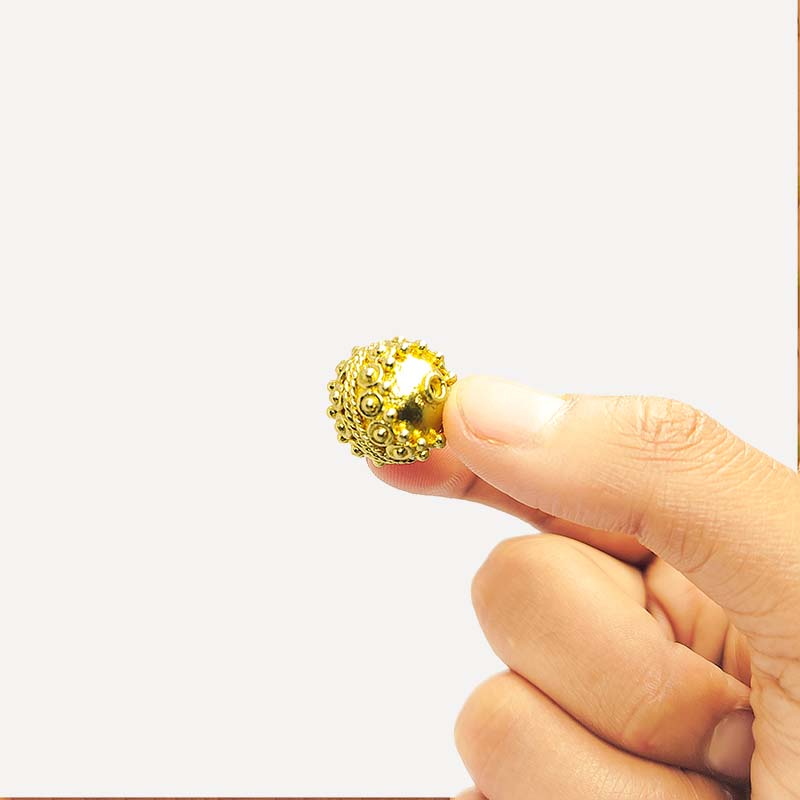 Handcrafted 18K gold overlay copper bead with raised granulated texture from India for jewelry making.