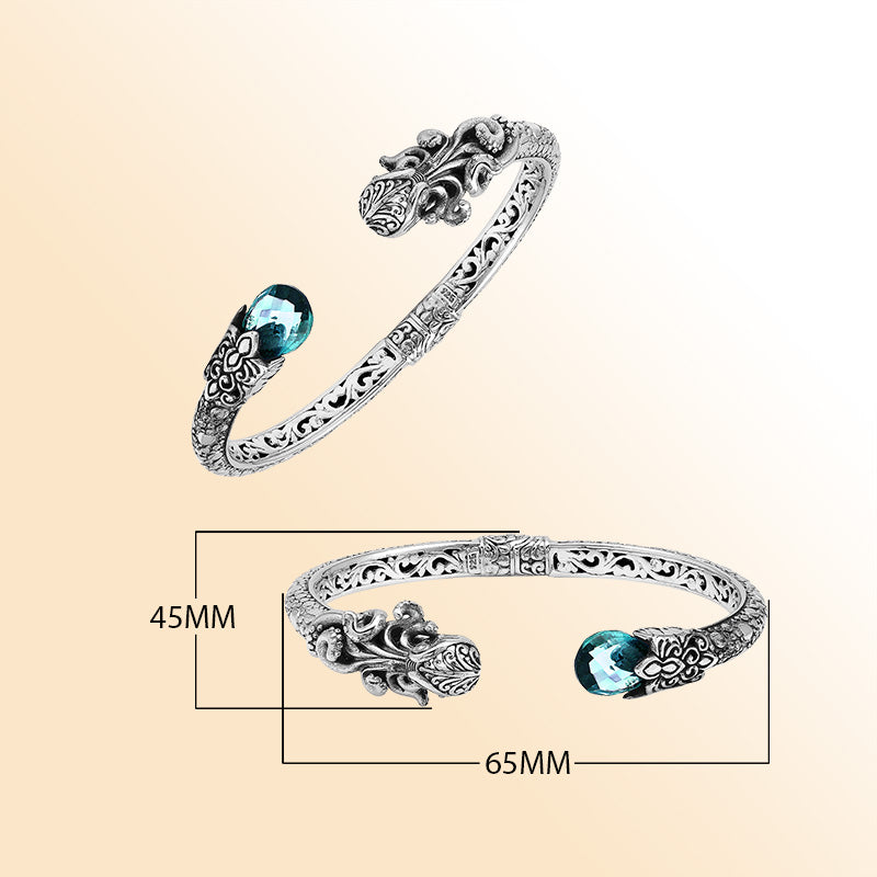 A handcrafted sterling silver octopus bangle featuring blue topaz quartz, ornate Balinese carvings, oxidized textures, and a secure hinge lock for elegant statement wear.