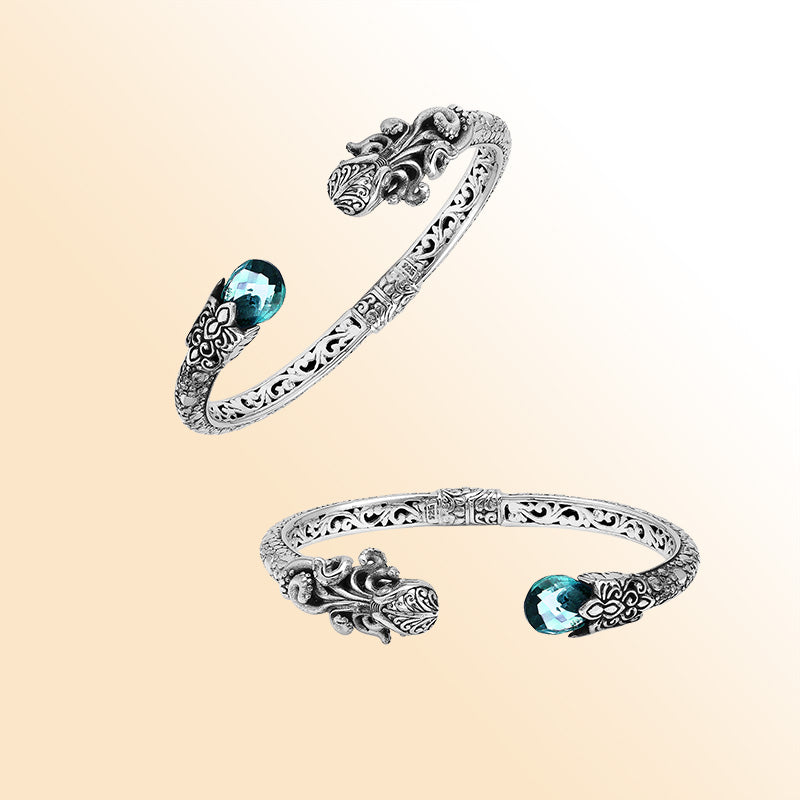 A handcrafted sterling silver octopus bangle featuring blue topaz quartz, ornate Balinese carvings, oxidized textures, and a secure hinge lock for elegant statement wear.