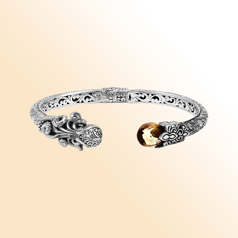 A handcrafted sterling silver octopus bangle featuring citrine quartz, ornate Balinese tentacle carvings, oxidized detailing, and a smooth hinge lock for stylish luxury wear.