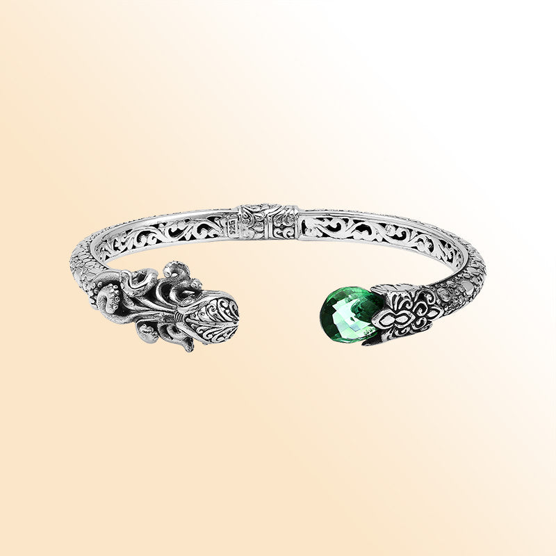 A handcrafted sterling silver octopus bangle featuring a vibrant green quartz gemstone, detailed tentacle carvings, oxidized Balinese patterns, and a smooth hinge lock for refined everyday wear.