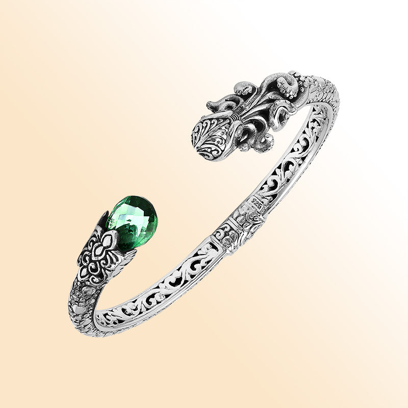 A handcrafted sterling silver octopus bangle featuring a vibrant green quartz gemstone, detailed tentacle carvings, oxidized Balinese patterns, and a smooth hinge lock for refined everyday wear.