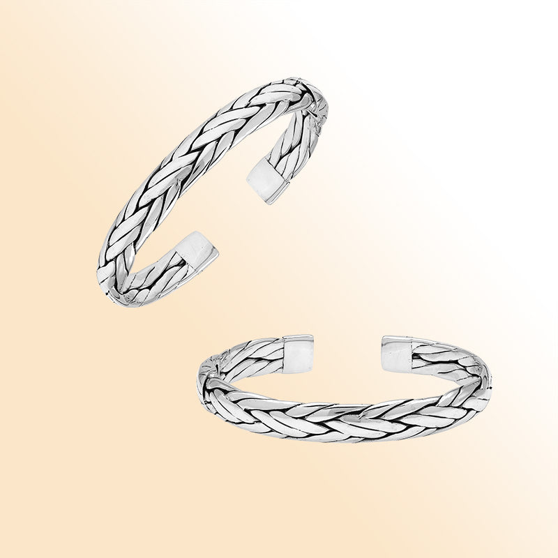 A handcrafted sterling silver large bangle featuring wide woven patterns, polished surfaces, and a secure hinge lock, designed for elegant everyday or statement wear.