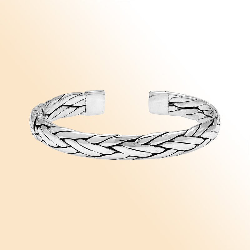 A handcrafted sterling silver large bangle featuring wide woven patterns, polished surfaces, and a secure hinge lock, designed for elegant everyday or statement wear.