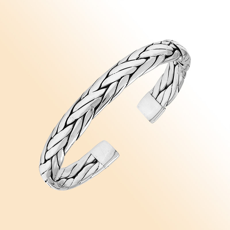 A handcrafted sterling silver large bangle featuring wide woven patterns, polished surfaces, and a secure hinge lock, designed for elegant everyday or statement wear.