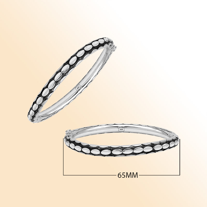 Handcrafted sterling silver medium bangle with elegant oval textured detailing, polished shine, and a secure hinge lock with safety latch for stylish daily wear.