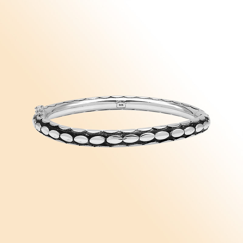 Handcrafted sterling silver medium bangle with elegant oval textured detailing, polished shine, and a secure hinge lock with safety latch for stylish daily wear.