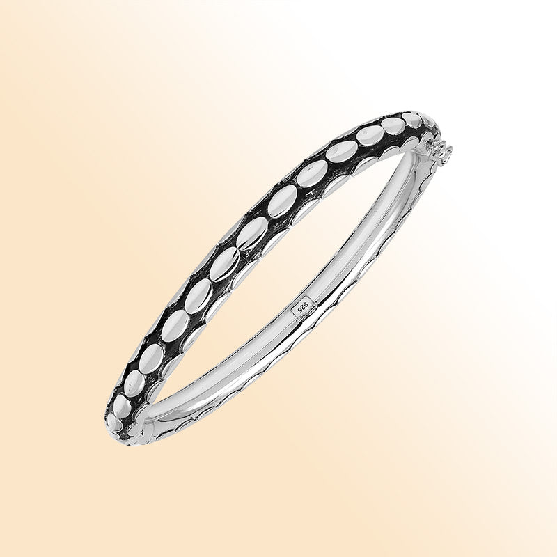 Handcrafted sterling silver medium bangle with elegant oval textured detailing, polished shine, and a secure hinge lock with safety latch for stylish daily wear.