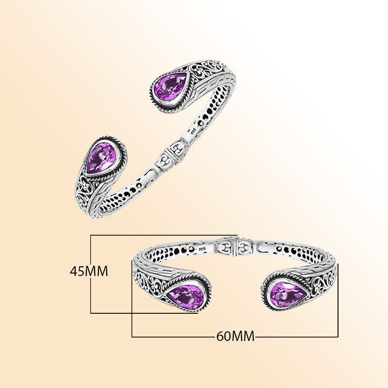 Handcrafted sterling silver bangle with teardrop amethyst quartz stones, intricate Bali engraving, polished shine, and a secure hinge lock for elegant everyday wear.