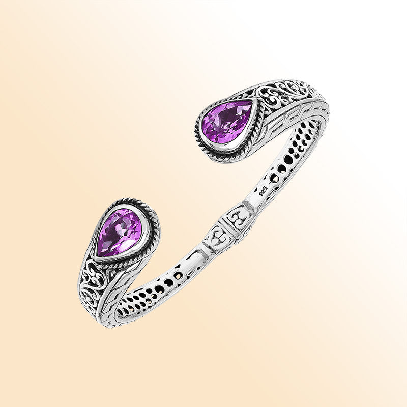 Handcrafted sterling silver bangle with teardrop amethyst quartz stones, intricate Bali engraving, polished shine, and a secure hinge lock for elegant everyday wear.