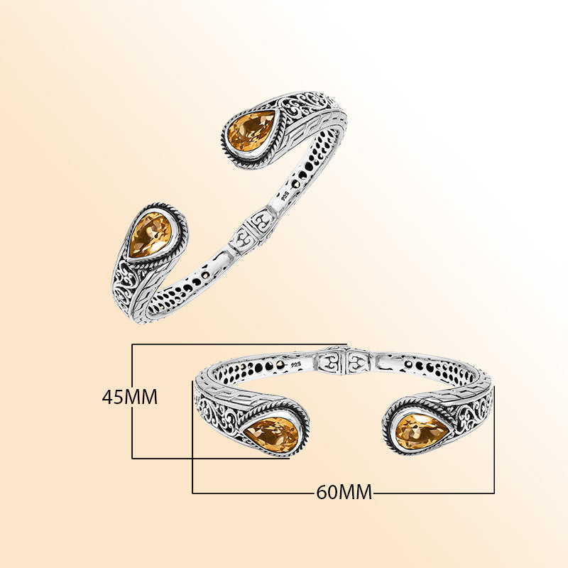 Handcrafted sterling silver bangle with teardrop citrine quartz stones, ornate Bali engraving, polished shine, and a secure hinge lock designed for elegant everyday wear.