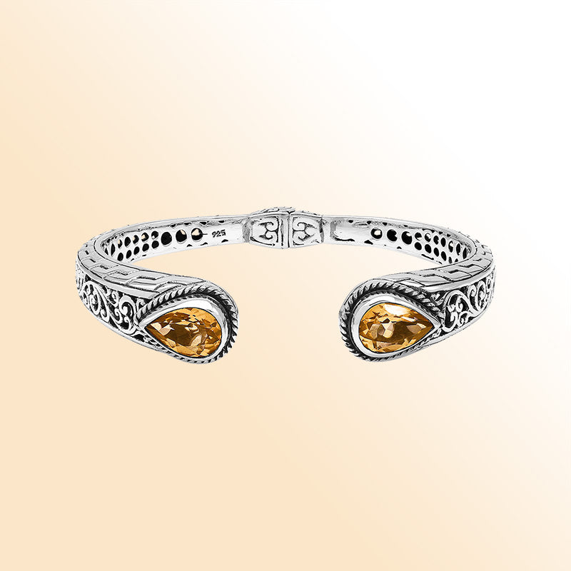 Handcrafted sterling silver bangle with teardrop citrine quartz stones, ornate Bali engraving, polished shine, and a secure hinge lock designed for elegant everyday wear.