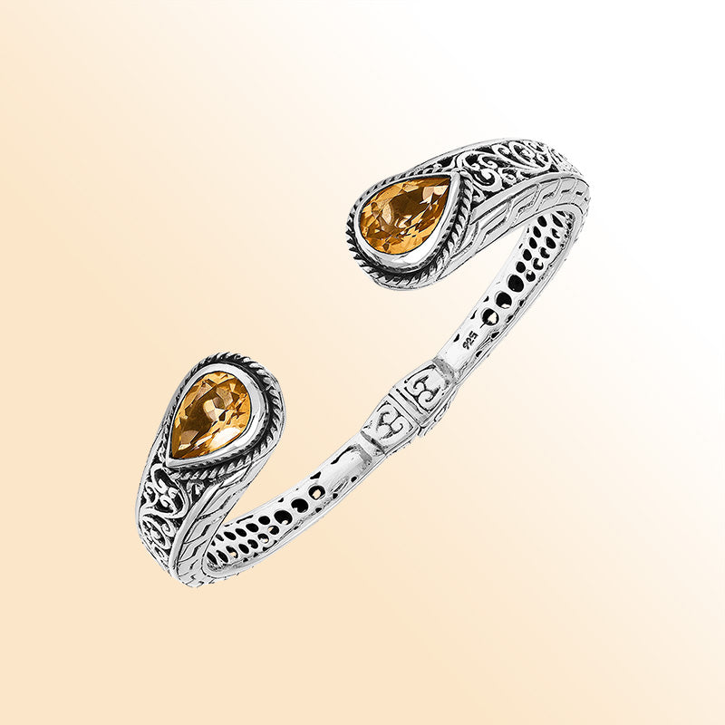 Handcrafted sterling silver bangle with teardrop citrine quartz stones, ornate Bali engraving, polished shine, and a secure hinge lock designed for elegant everyday wear.