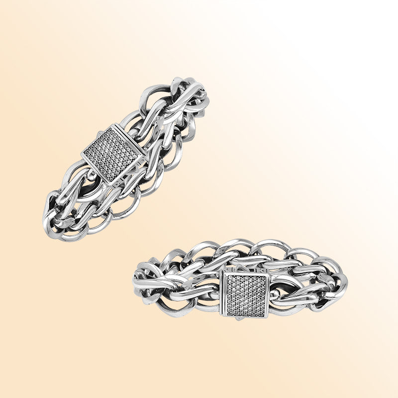 A handcrafted sterling silver woven bracelet featuring a pavé Cubic Zirconia push clasp, polished bold links, and a modern statement style designed for elegant everyday wear.