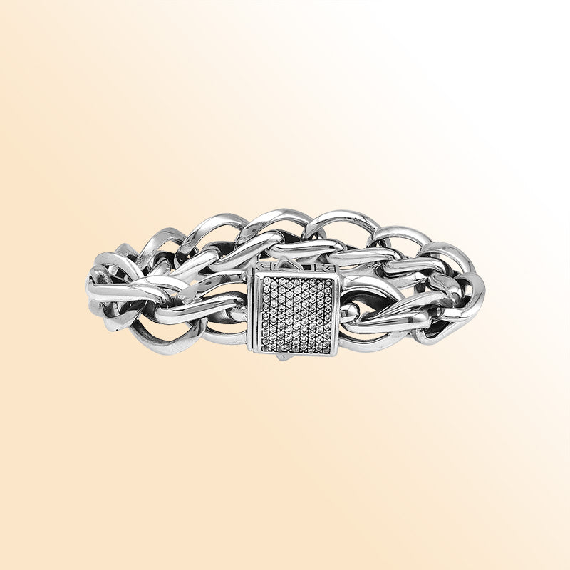 A handcrafted sterling silver woven bracelet featuring a pavé Cubic Zirconia push clasp, polished bold links, and a modern statement style designed for elegant everyday wear.