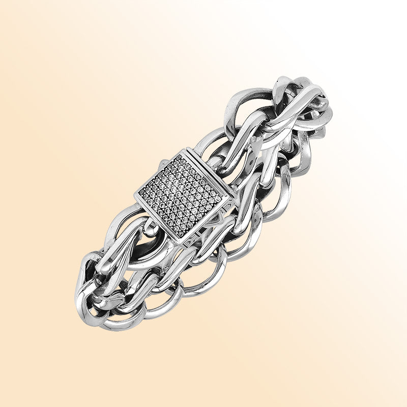 A handcrafted sterling silver woven bracelet featuring a pavé Cubic Zirconia push clasp, polished bold links, and a modern statement style designed for elegant everyday wear.