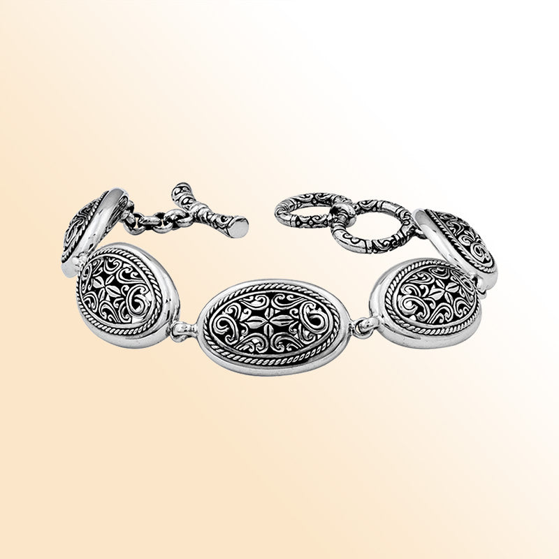 Sterling Silver oval scroll bracelet with sculpted artistic detailing, polished toggle closure, and a high-gloss shine reflecting Balinese-inspired craftsmanship and elegant styling.