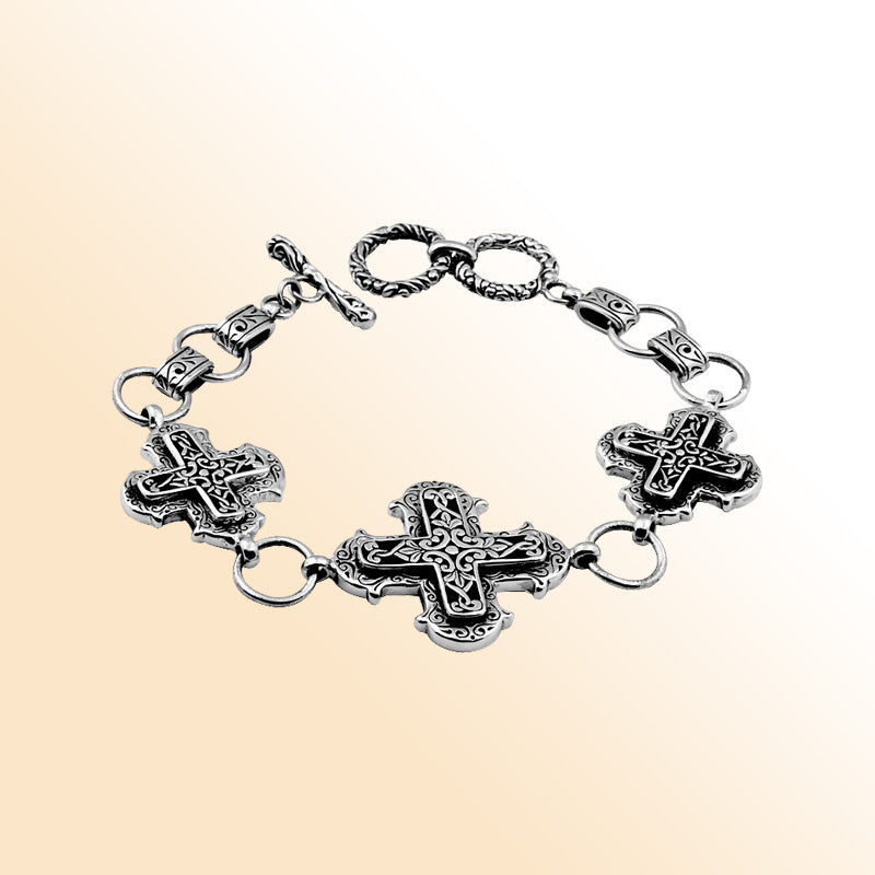 Sterling Silver artistic bracelet featuring sculpted cross-shaped panels with flowing scrollwork, polished linking rings, and a smooth toggle closure inspired by Balinese artistry.