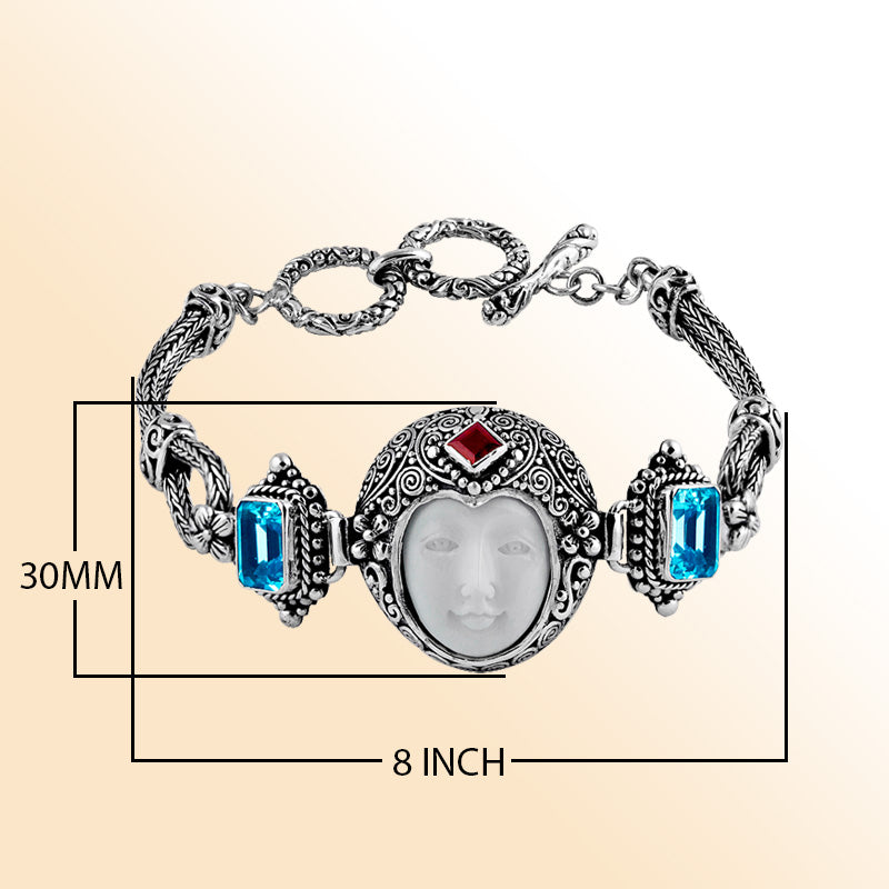 Sterling Silver bracelet showcasing an artistic carved bone face centerpiece with Red Garnet Quartz and Blue Topaz Quartz accents framed by intricate Balinese scrollwork.