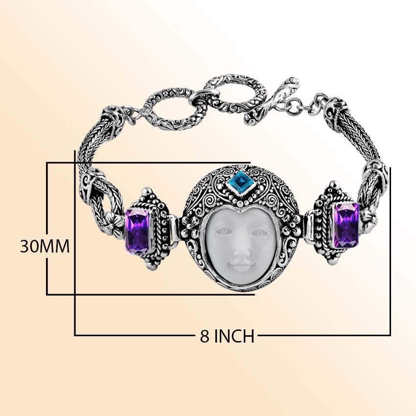 Sterling Silver bracelet featuring an artistic carved bone face centerpiece with Garnet Quartz and Blue Topaz Quartz accents and ornate Balinese scroll detailing.