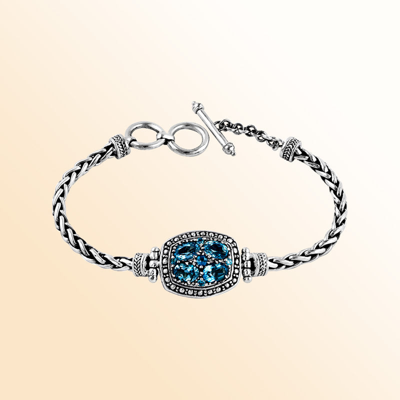 Sterling Silver artistic bracelet showcasing a Blue Topaz Quartz cluster centerpiece, intricately braided chain, and a polished toggle closure inspired by Balinese craftsmanship.