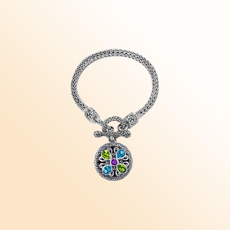 An artisan sterling silver bracelet featuring a woven chain and colorful pendant set with Amethyst Quartz, Blue Topaz Quartz, and Peridot Quartz, paired with a classic toggle lock for stylish everyday wear.