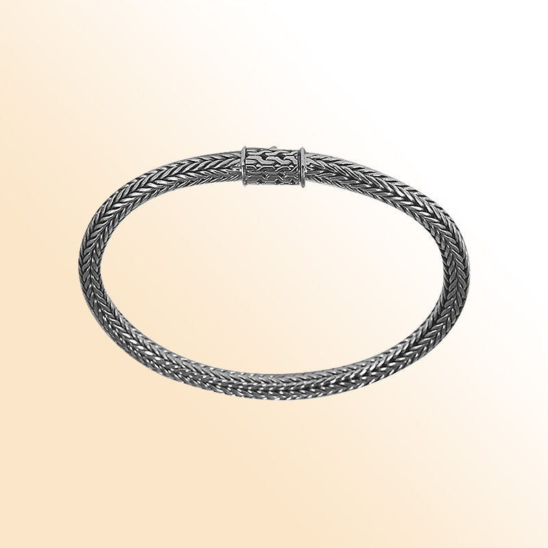 Elegant sterling silver woven bracelet featuring a polished surface, smooth chain pattern, and secure push clasp for refined everyday styling.