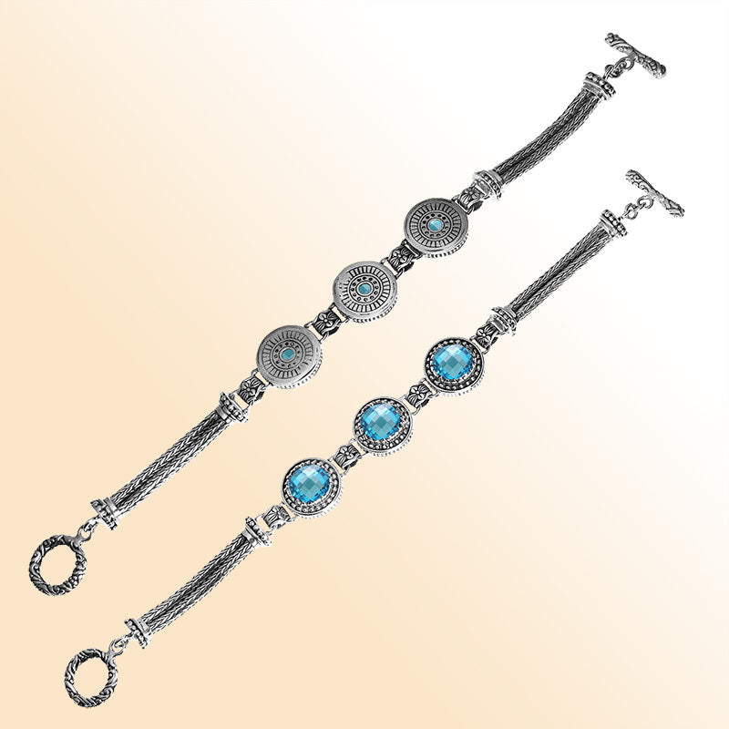 Sterling silver bracelet with faceted Blue Topaz Quartz, circular artisan motifs, braided chain work, and a decorative toggle lock.