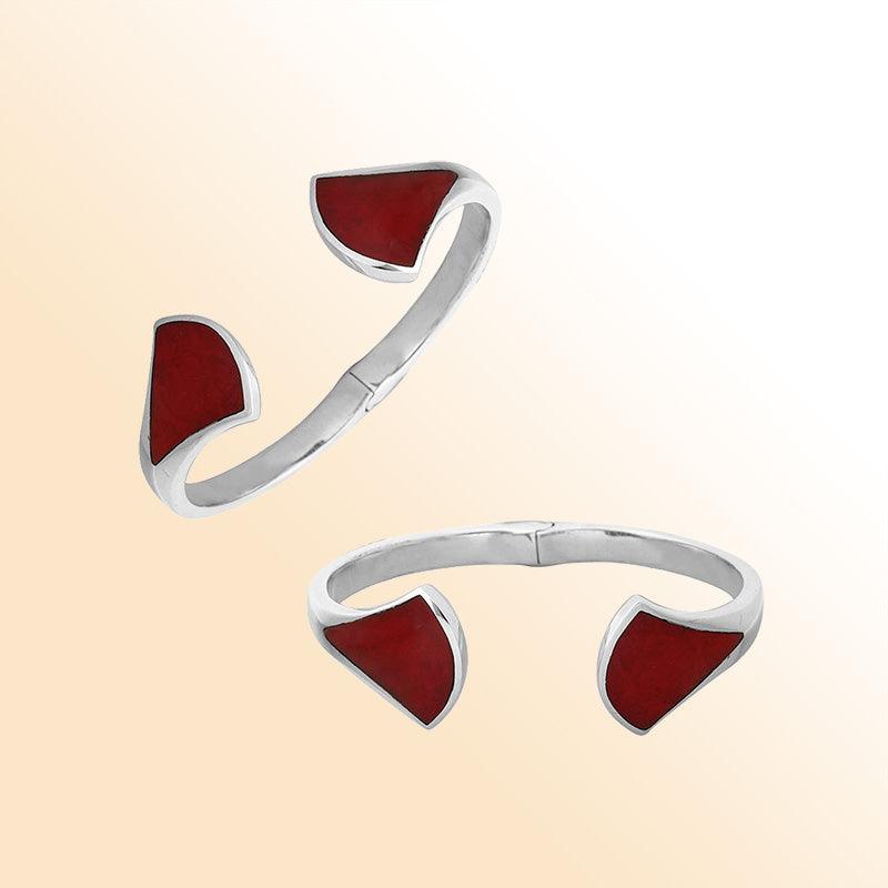 Retail sterling silver cuff showcasing vibrant Red Coral inlays on sculpted open ends with a polished finish and hinge lock for elegant daily styling.
