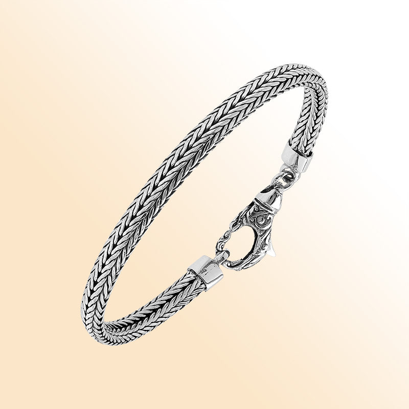 An elegant sterling silver braided chain bracelet with an artistic lobster clasp, featuring smooth texture, high-gloss polish, and intricate craftsmanship ideal for timeless modern style.