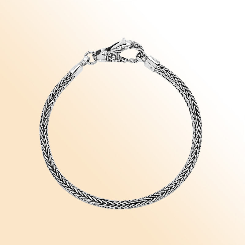An elegant sterling silver braided chain bracelet with an artistic lobster clasp, featuring smooth texture, high-gloss polish, and intricate craftsmanship ideal for timeless modern style.