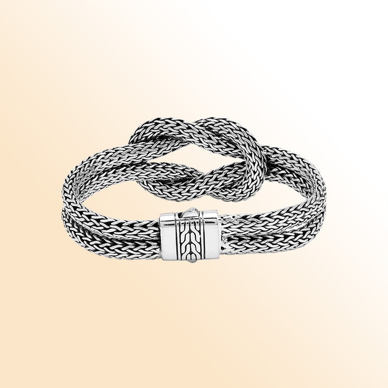 Handcrafted sterling silver woven knot bangle featuring a multi-strand Balinese chain weave design with a secure push clasp, offering symbolic beauty and bold artisan craftsmanship.