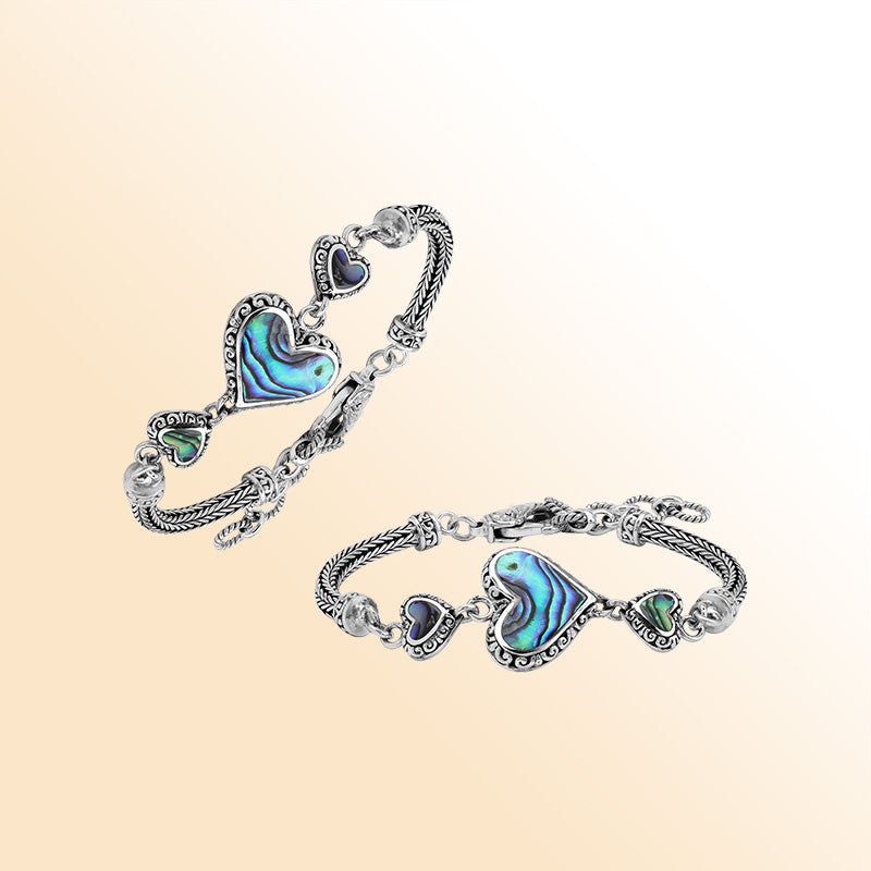 Handcrafted sterling silver bracelet featuring Abalone Shell heart motifs, ornate Balinese scrollwork, and a secure lobster lock for colorful, expressive, artisan-inspired everyday style.