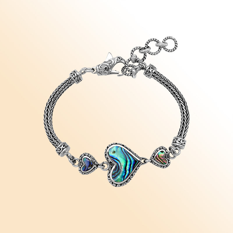 Handcrafted sterling silver bracelet featuring Abalone Shell heart motifs, ornate Balinese scrollwork, and a secure lobster lock for colorful, expressive, artisan-inspired everyday style.