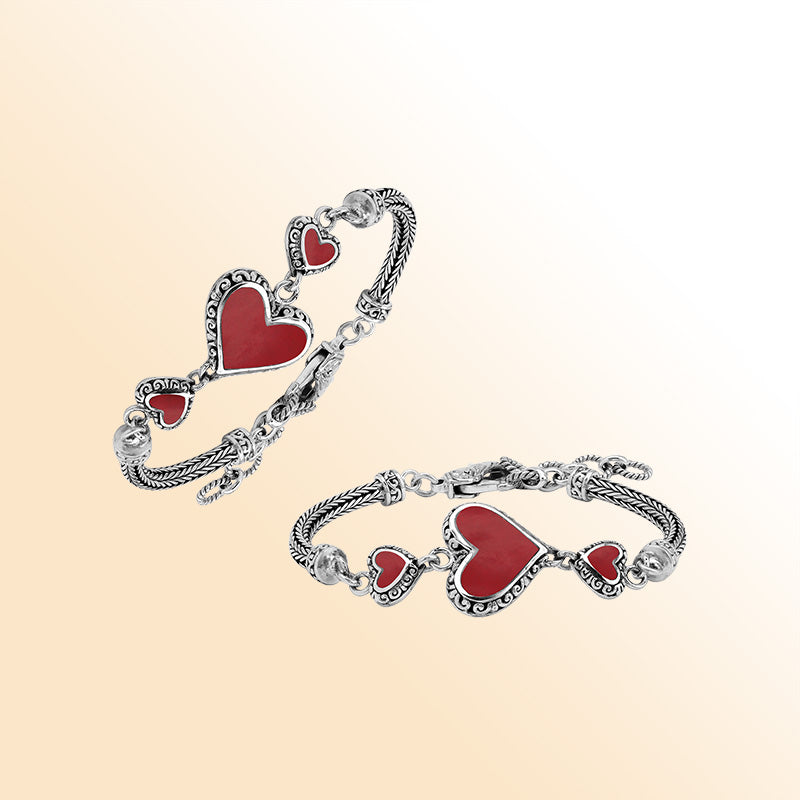 Handcrafted sterling silver bracelet featuring Red Coral heart motifs, ornate Balinese scroll engravings, and a secure lobster lock for colorful, expressive, artisan-style everyday wear.