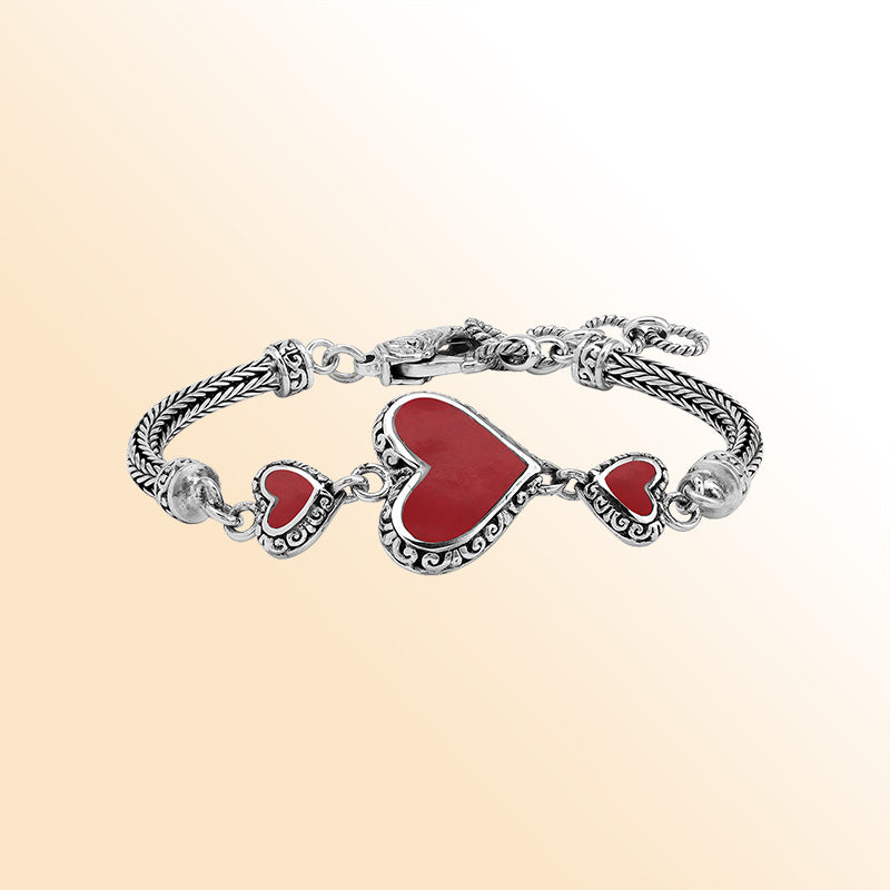 Handcrafted sterling silver bracelet featuring Red Coral heart motifs, ornate Balinese scroll engravings, and a secure lobster lock for colorful, expressive, artisan-style everyday wear.