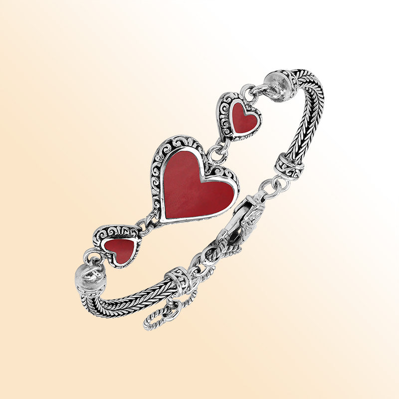 Handcrafted sterling silver bracelet featuring Red Coral heart motifs, ornate Balinese scroll engravings, and a secure lobster lock for colorful, expressive, artisan-style everyday wear.