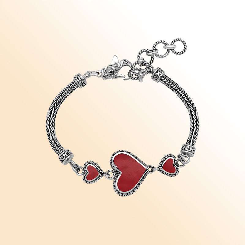 Handcrafted sterling silver bracelet featuring Red Coral heart motifs, ornate Balinese scroll engravings, and a secure lobster lock for colorful, expressive, artisan-style everyday wear.